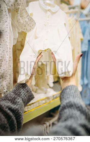 Female person chooses baby clothes in the store