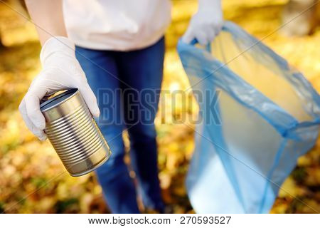 Volunteer Picking Up The Metal Garbage And Putting It In Biodegradable Trash-bag On Outdoors. Ecolog