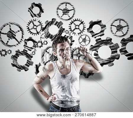 Confused Mechanic Holding A Wrench In Front Of A White Wall. Wall Drawn With A Engine Wheels Gear.