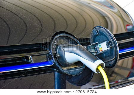 A Electric Vehicle Is Charged At A Charging Station. The Charging Plug Is Plugged Into The Socket Hi