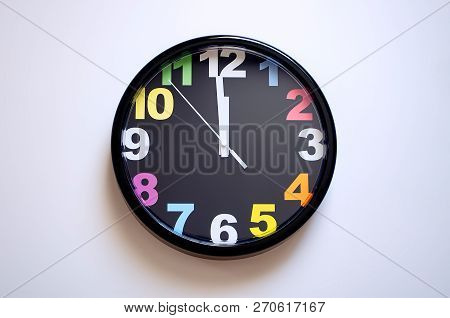 Clock On A White Background. A Few Seconds To Midnight. Multi-colored Numbers On The Clock.
