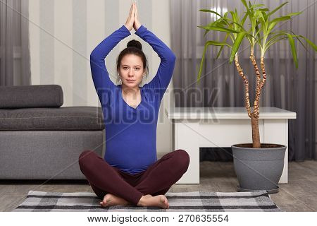 Yoga, Fitness, Lifestyle And Pregnancy Concept. Pregnant Girl Exercises At Home, Meditates Indoor On