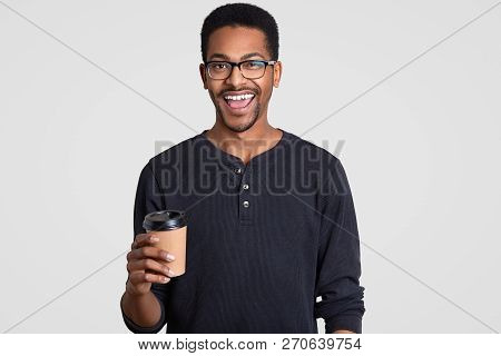 Image Of Happy Smiling Teenge Boy With Dark Skin, Wears Spectacles, Holds Takeout Coffee, Enjoys Fre