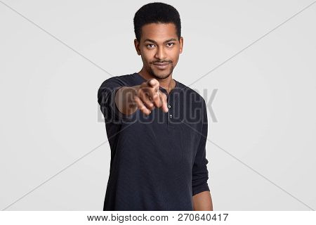 Image Of Self Assured Dark Skinned Man Points With Index Finger Directly At Camera, Hints At Somethi