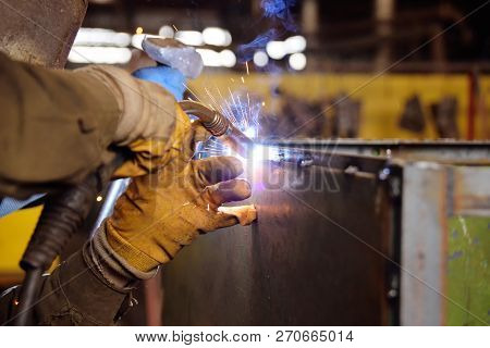Welder For His Work. Welding Sparks On Production Background