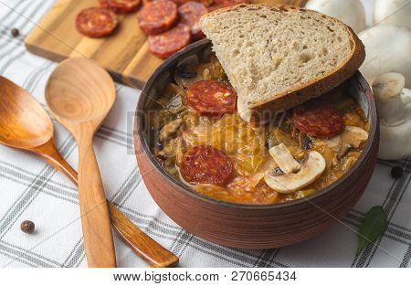 Slovak Christmas National Cabbage Soup In Ceramic Bowl With Sausage On The Tablecloth Background.