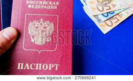 Image Of A Persons Hand Holding Russian Passport On The Blue Textile Background . And Euro Banknotes