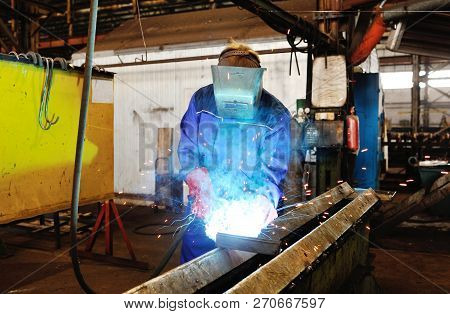 Welder With Welding Machine In The Background Of The Plant