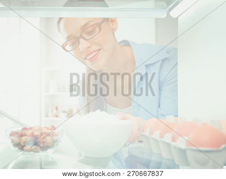 Portrait Of Female Standing Near Open Fridge Full Of Healthy Food, Vegetables And Fruits. Portrait O