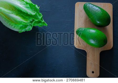 Fresh Avocado On A Cutting Board With Lettuce Leaves On A Wooden Background. Healthy Food.copy Space