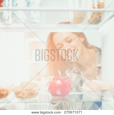 Portrait Of Female Standing Near Open Fridge Full Of Healthy Food, Vegetables And Fruits. Portrait O