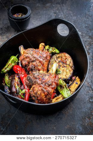 Traditional barbecue leg of lamb with eggplant and chili as top view in a modern style Japanese cast-iron roasting dish 