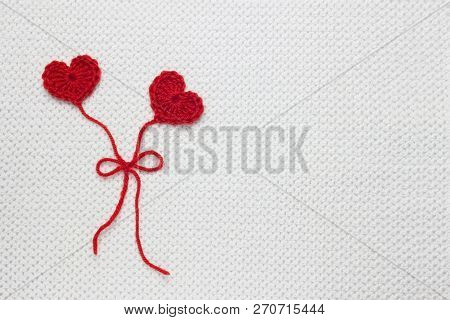 Two Red Crochet Wool Hearts And Ribbon On White Crochet Background, Love Story. The Concept For 14 F