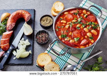 Beans Stew With Sausages, Herbs And Spices In Tomato Sauce In A Metal Casserole On A Concrete Table 
