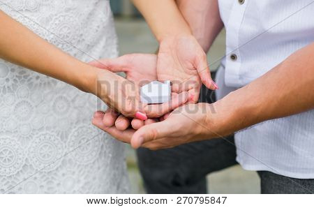 A Man And A Woman Holding In Their Hands A Small House. Close Up. Horizontal Photography