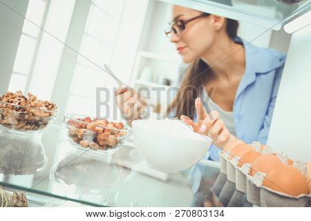 Portrait of female standing near open fridge full of healthy food, vegetables and fruits. Portrait of female