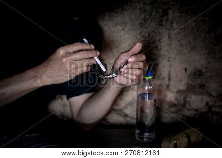 Man Makes Heroin, Preparing To Take Heroin, Pours Heroin Into A Spoon. The Concept Of Crime And Drug