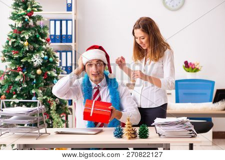 Colleagues exchaing christmas presents in office