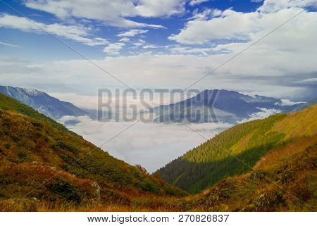 Landscape - View From The Mountain Top On A Sunny Day To The Valley Hidden By Low Clouds