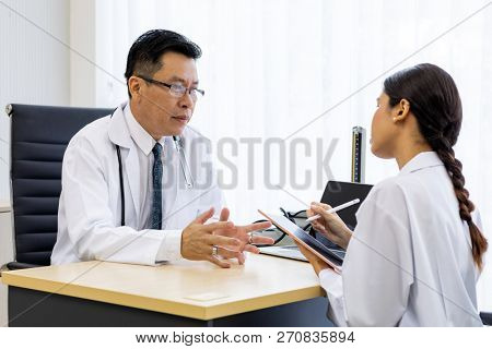 Two doctors in the hospital discuss the diagnos of the patient