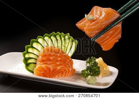 Close Up Salmon Sashimi With Salmon In A White Plate. On A Black Background