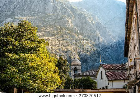 Mountains Rise Above The Belfry Of Saint Claire Church With The Dome Of The St. Nicholas Church Alon