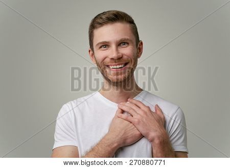 A Good-natured Attractive Young Guy Has A Friendly Expression, Holds Hands On Heart, Expresses Feeli