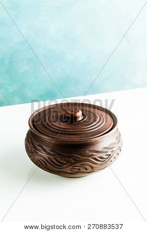 Pots And Plates Of Clay On A White Table And A Blue Background. Clay Pottery Kitchen Utensils Made B