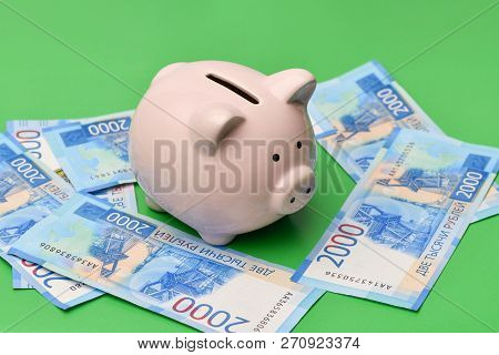 A Pink Piggy Bank In The Shape Of A Pig Stands In The Center On A Green Background And Russian Money