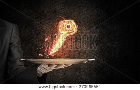 Cropped Image Of Waitresss Hand In White Glove Presenting Flaming Key Symbol On Metal Tray With Dark