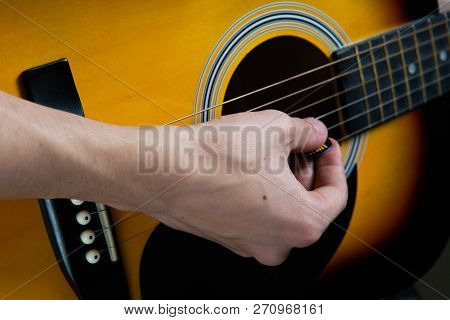 Hand Of Man Playing Six-string Guitar On Wooden Background.