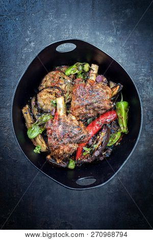 Traditional barbecue leg of lamb with eggplant and chili as top view in a modern style Japanese cast-iron roasting dish with copy space 
