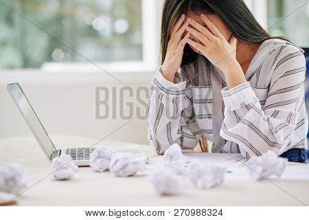 Brunette In Blouse Covering Face With Hands Being Upset Of Failure While Writing Paper At Table With