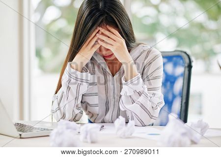 Young Stylish Woman Leaning On Hands While Sitting At Table With Crumpled Papers Around Being Uninsp