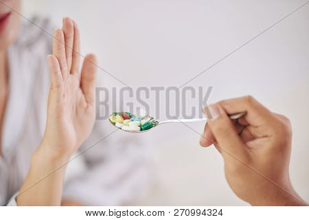 Crop Shot Of Rejecting Palm Of Woman Unwilling To Take Spoon Of Pills