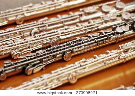 Set Of Silver Flutes On The Wooden Table Horizontal Close Up. Musik Background. Selected Focus.