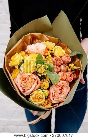 Bouquet Of Flowers In Pistachio-colored Package In The Hands Of A Woman Florist On Background A Whit