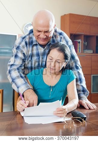 Mature Woman Fills Documents, Elferly Man Helping Her At Home