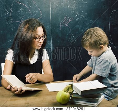Little Cute Boy In Glasses With Young Real Teacher, Classroom Studying At Blackboard School Kido