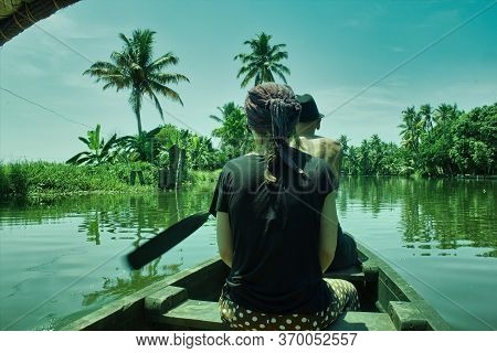 A French Man Tourist Riding A Boat Manually With A Girl In The Backwaters Of Allepey Town, Located I