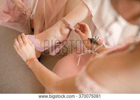 A Girlfriend Helps A Bride To Put On Her Wedding Shoes. Beautiful Female Feet Closeup.