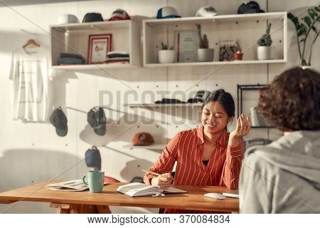 Portrait Of Young Female Worker Writing Notes While Listening To Male Customer In The Office. Woman 