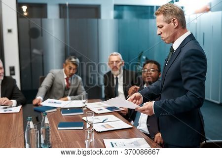 Disappointed Mature Businessman In Formal Wear Holding Some Documet And Discussing Something With Mu