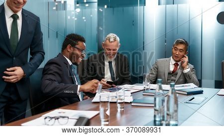 Happy Multicultural Business People In Formal Wear Talking About Something And Smiling While Having 