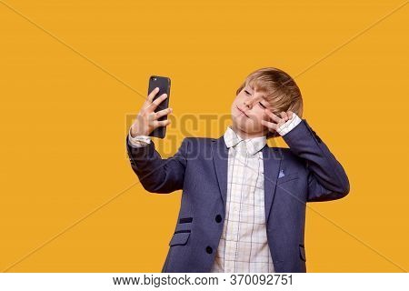 The Child Takes A Selfie With A Phone In His Hands And A Beautiful Business Suit