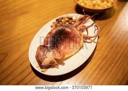 Korean Traditional Snack To Consume With Sojo Alcohol. Korean Style Grilled Squid And Peanuts On A W