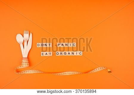 Diet And Healthy Eating Concept - Wooden Cutlery, Yellow Measuring Tape And Words Dont Panic Eat Org