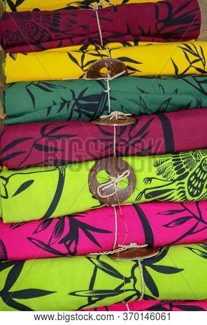 Rolled Up Colored Fabrics Tied With String. Shop With Brightly Colored Sarongs. Sarung Pantai Ready 
