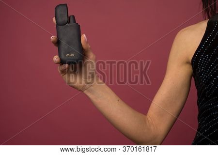Tula, Russia - June 06 2020: Woman With E-cigarette. Heating Tobacco System Iqos Product Technologie
