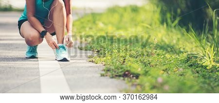 Running Woman Tying Laces Of Running Shoes Before Jogging Through The Road In The Workout Nature Par